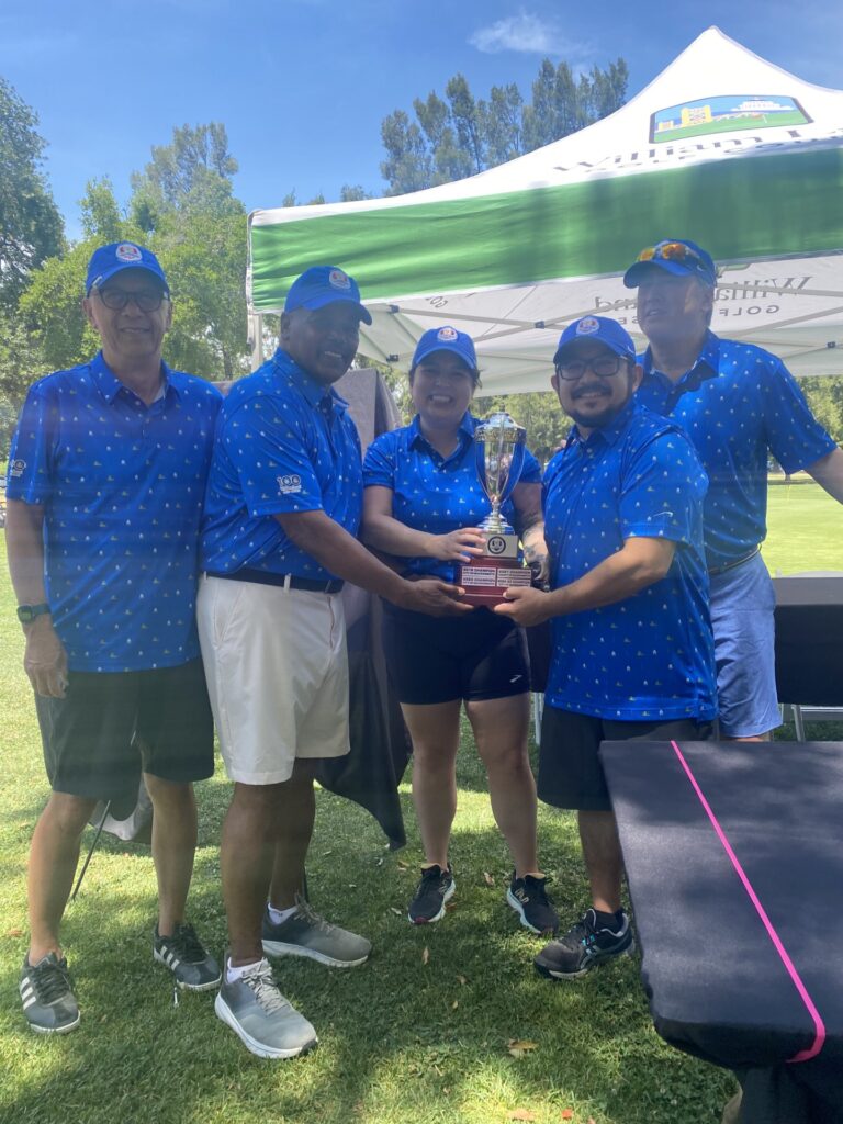 Winning team at golf tournament holding trophy 